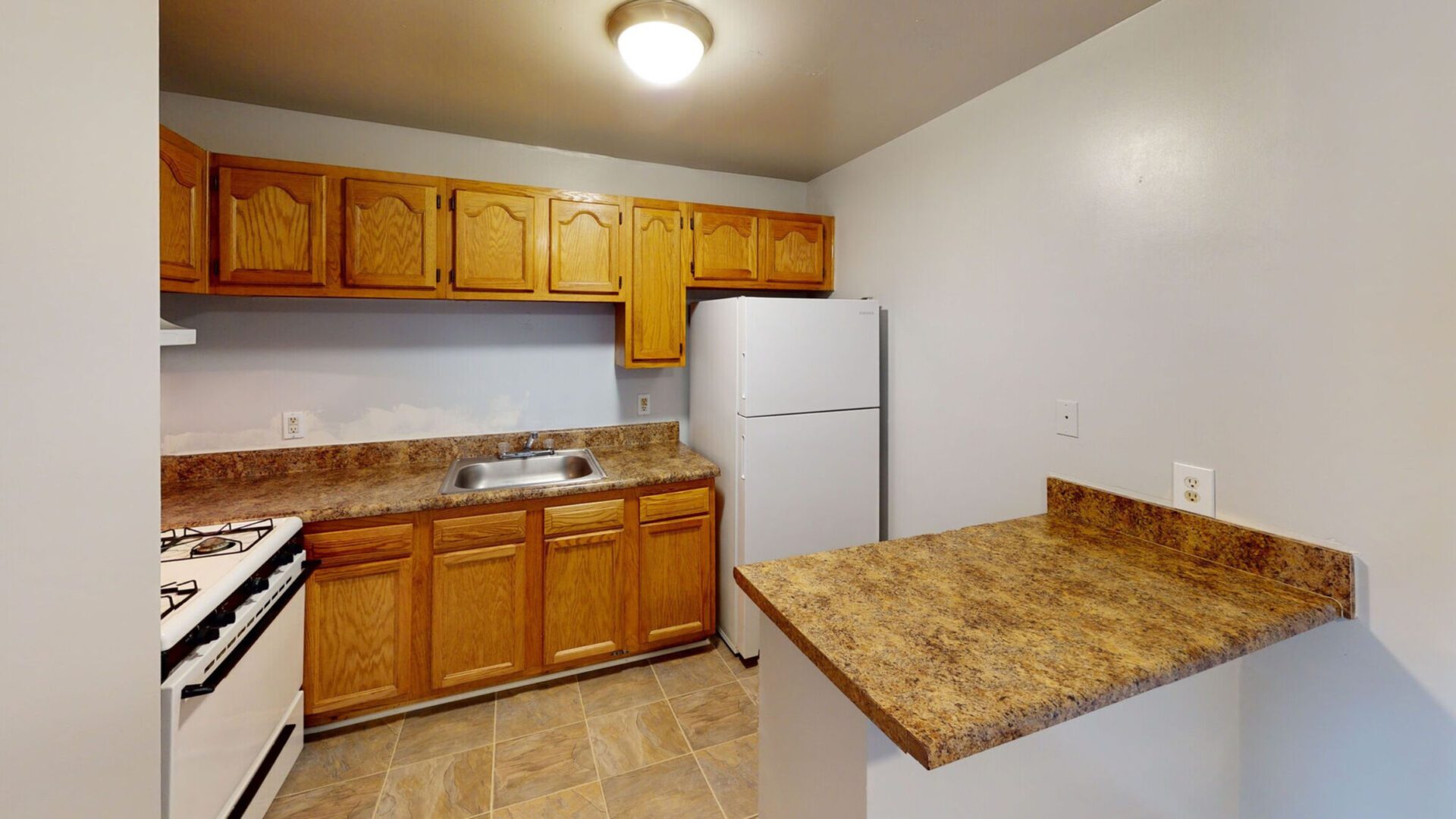 A modern kitchen featuring a refrigerator, stove, and sink, showcasing a functional and organized cooking space